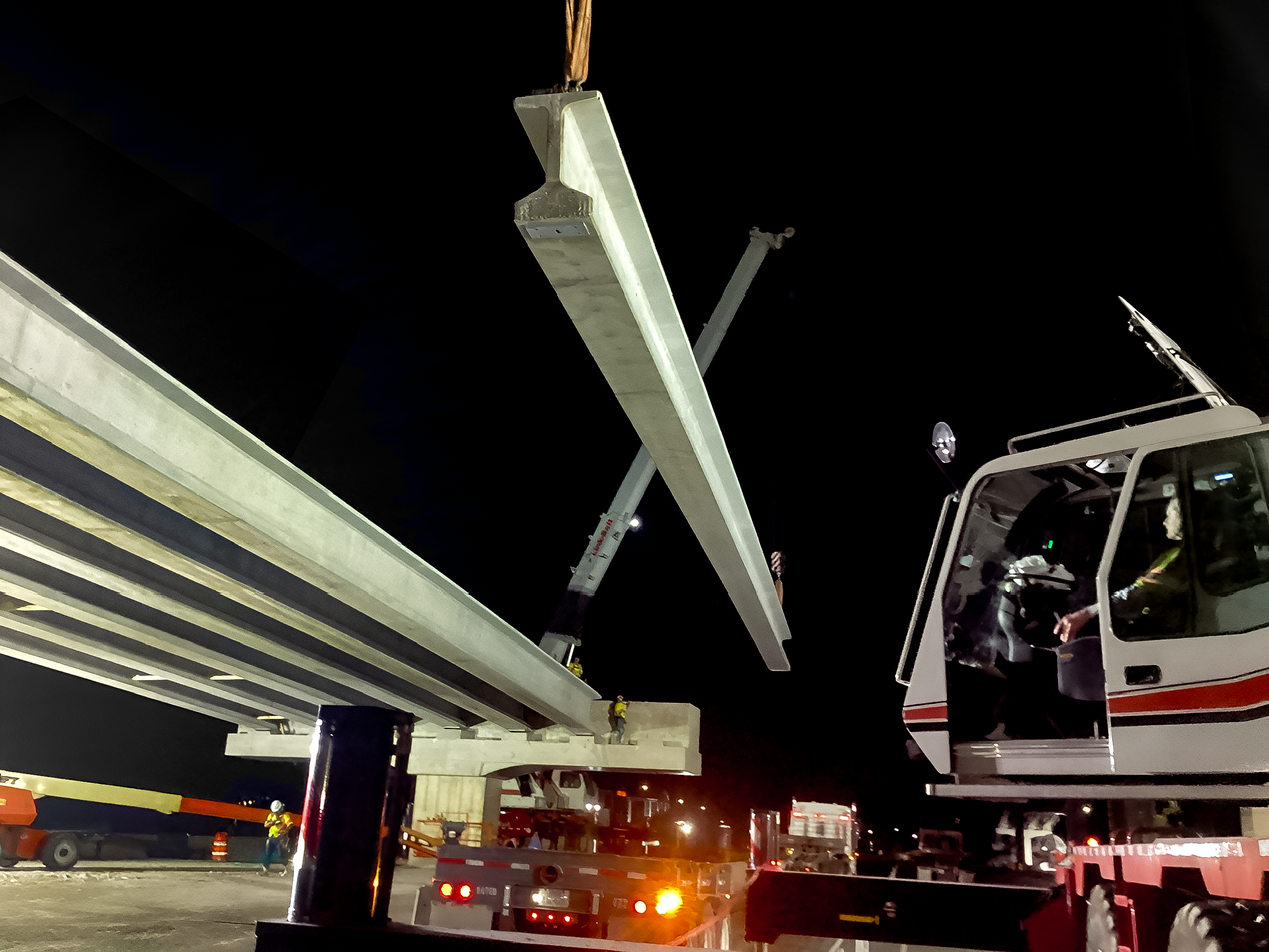 Photo of workers installing the last precast girder on the beam